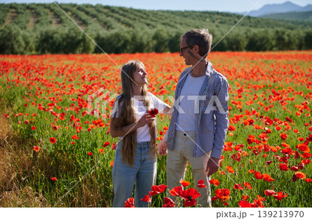 Smiling Man And Young Woman Walking Together In A Vibrant Red Poppy Field Smiling Man And Young Woman Walking Together In A Vibrant Red Poppy Field 139213970