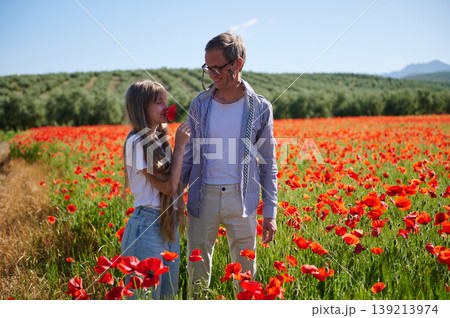 Father And Daughter Walking Through Red Poppy Field On Sunny Summer Day Father And Daughter Walking Through Red Poppy Field On Sunny Summer Day 139213974