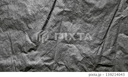 crumpled gray paper texture closeup with intricate folds creases and shadows in minimalist monochrome composition 139214043