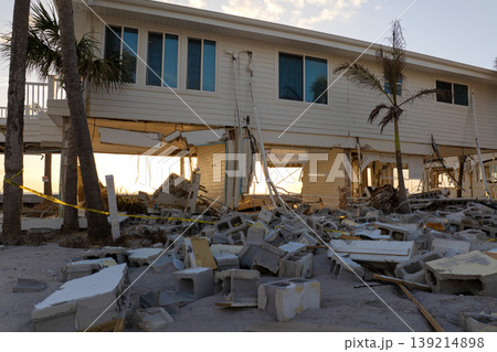 Storm surge caused by hurricane wind severe damaged residential houses on ocean shore. Natural disaster consequences in Florida Storm surge caused by hurricane wind severe damaged residential houses on ocean shore. Natural disaster consequences in Florida 139214898
