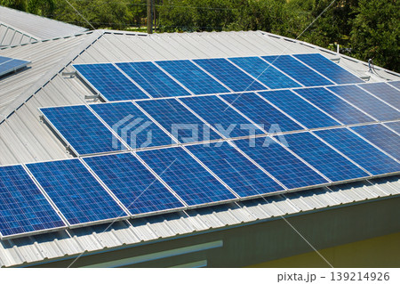 Solar panels on residential house rooftop. Photovoltaic sells for producing of clean electrical energy in suburban rural area. Concept of investment in autonomous home Solar panels on residential house rooftop. Photovoltaic sells for producing of clean electrical energy in suburban rural area. Concept of investment in autonomous home 139214926