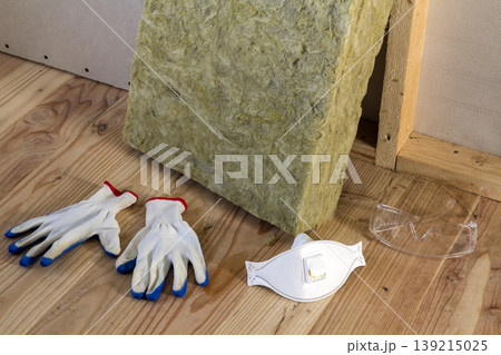 Rock wool and fiberglass insulation staff material for cold barrier. Tools for work with glass wool: protective goggles, glasses and mask. Warm home, economy, construction and renovation concept. 139215025