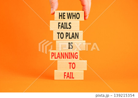 Planning to fail symbol. Concept words He who fails to plan is planning to fail on beautiful wooden blocks. Beautiful orange background. Businessman hand. Business planning to fail concept. Copy space 139215354