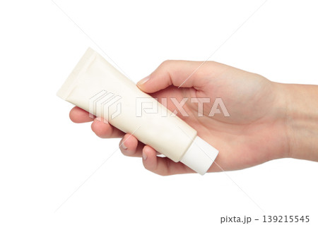 Beige cream tube in woman hands isolated on white background. Skin care concept. Beige cream tube in woman hands isolated on white background. Skin care concept. 139215545