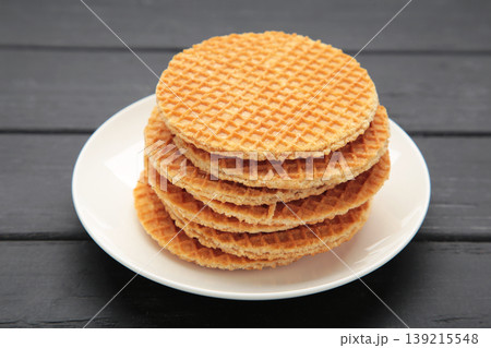 Stack of Dutch stroop wafel cookies or caramel waffles on plate on black background. Space for text Stack of Dutch stroop wafel cookies or caramel waffles on plate on black background. Space for text 139215548