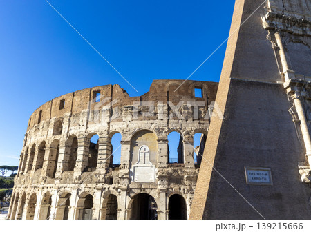 Famous Coliseum in Rome. Colosseum, or Coliseum. Part of the wall of an antique stone structure with arches. Italy, Europe. Famous touristic place in the world, Europe. Beautiful blue sky background. Famous Coliseum in Rome. Colosseum, or Coliseum. Part of the wall of an antique stone structure with arches. Italy, Europe. Famous touristic place in the world, Europe. Beautiful blue sky background. 139215666