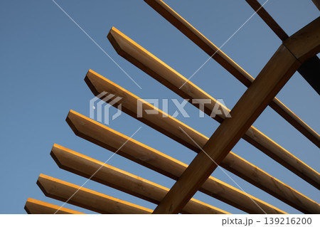 Abstract closeup of wooden pergola lattice slats geometric pattern against clear blue sky 139216200