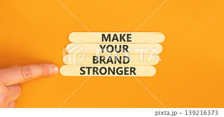 Make your brand stronger symbol. Concept words Make your brand stronger on beautiful wooden sticks. Beautiful orange background. Businessman hand. Business make your brand stronger concept. Copy space Make your brand stronger symbol. Concept words Make your brand stronger on beautiful wooden sticks. Beautiful orange background. Businessman hand. Business make your brand stronger concept. Copy space 139216373