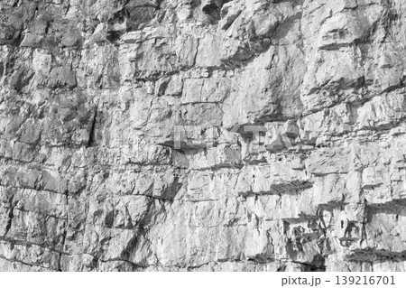 A close-up view of a rugged gray cliff wall showing layered stones 139216701