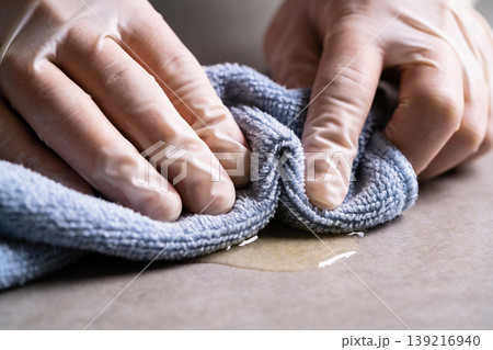 Close-up of hands wearing protective gloves wiping a spill with a blue cloth Close-up of hands wearing protective gloves wiping a spill with a blue cloth 139216940