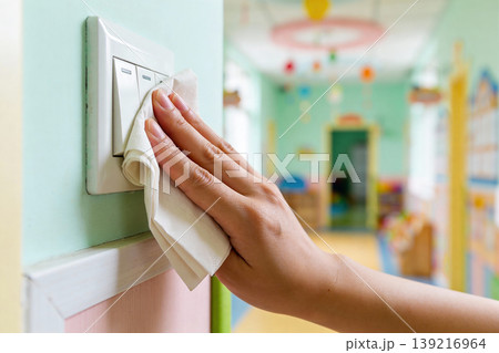 Hand cleaning a light switch with a white cloth in a brightly colored room Hand cleaning a light switch with a white cloth in a brightly colored room 139216964