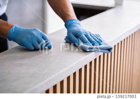 Person wearing blue gloves wipes down a counter with a microfiber cloth Person wearing blue gloves wipes down a counter with a microfiber cloth 139217001