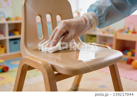 Disinfecting a child's chair in a classroom with a wipe and gloved hand Disinfecting a child's chair in a classroom with a wipe and gloved hand 139217044