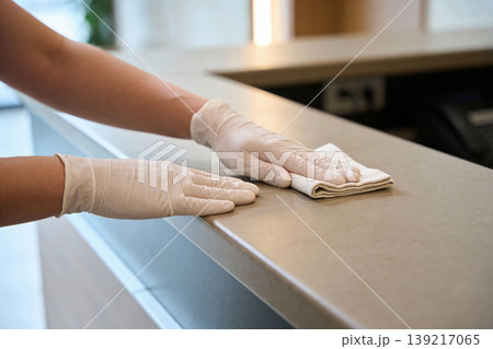 Hands wearing white gloves wiping down a counter with a cloth for hygiene and cleanliness Hands wearing white gloves wiping down a counter with a cloth for hygiene and cleanliness 139217065