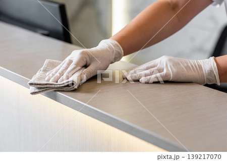 Close-up of hands in white gloves cleaning a reception desk with a cloth 139217070