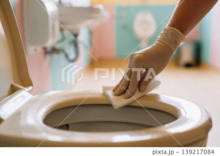 Hand wearing glove cleaning toilet seat with wet wipe for hygiene and sanitation Hand wearing glove cleaning toilet seat with wet wipe for hygiene and sanitation 139217084