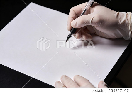 Hand wearing white glove writing on blank paper with pen, close-up shot 139217107