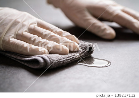 Hands wearing white gloves wiping a wet surface with a gray microfiber cloth Hands wearing white gloves wiping a wet surface with a gray microfiber cloth 139217112