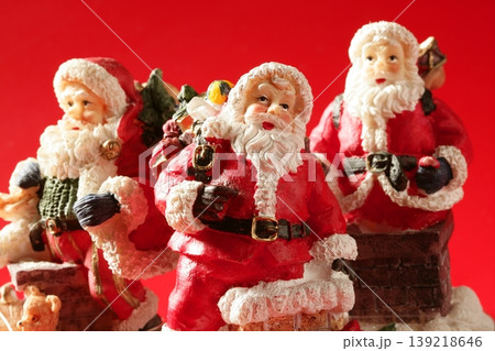 Three Santa Claus figurines over red background, studio Three Santa Claus figurines over red background, studio 139218646