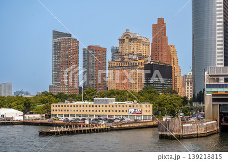 New york, usa august 16,2024. Manhattan skyline featuring historic and modern buildings behind the harbor, showing the staten island ferry terminal in foreground New york, usa august 16,2024. Manhattan skyline featuring historic and modern buildings behind the harbor, showing the staten island ferry terminal in foreground 139218815