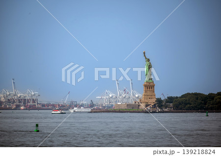 New york, usa august 16,2024. Statue of liberty overlooking new york harbor with ships, cranes and skylinesymbol of immigration, freedom and commerce New york, usa august 16,2024. Statue of liberty overlooking new york harbor with ships, cranes and skylinesymbol of immigration, freedom and commerce 139218824