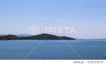 Bitez, Bodrum, Turkey coast presenting calm Aegean Sea water and green islands under clear sky Bitez, Bodrum, Turkey coast presenting calm Aegean Sea water and green islands under clear sky 139219254
