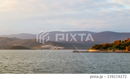 Gulluk bay seascape with people fishing on a pier, coastal town and mountains in Milas, Turkey Gulluk bay seascape with people fishing on a pier, coastal town and mountains in Milas, Turkey 139219272