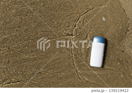 White bottle with blue cap in shallow beach water on sand with ripples White bottle with blue cap in shallow beach water on sand with ripples 139219422