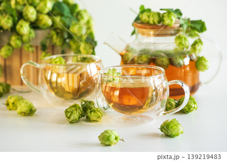 Hop Tea in Glass Teapot and Glass Cups on White Wooden Table 139219483