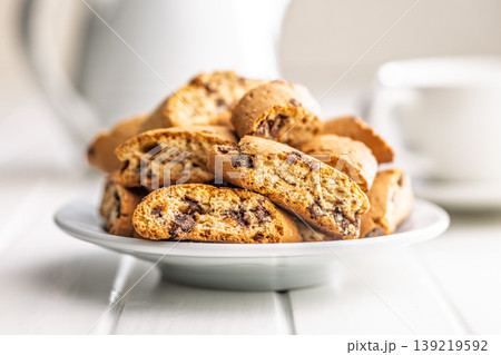 Grissini. Crispy Chocolate Chip Biscotti With Coffee Cup on White Table, Rustic Morning Snack and Dessert Grissini. Crispy Chocolate Chip Biscotti With Coffee Cup on White Table, Rustic Morning Snack and Dessert 139219592