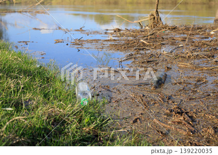 Plastic and glass bottles in shallow water. Concept of human pollution of rivers and lakes. Litter impacting nature, aquatic ecosystems Plastic and glass bottles in shallow water. Concept of human pollution of rivers and lakes. Litter impacting nature, aquatic ecosystems 139220035