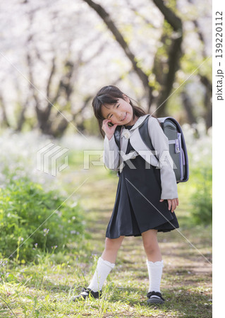 桜並木の中で笑顔を見せるランドセル姿の新一年生の女の子 桜並木の中で笑顔を見せるランドセル姿の新一年生の女の子 139220112