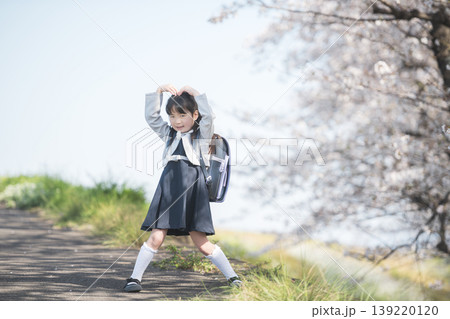 満開の桜並木でポーズを決めるランドセル姿の新一年生の女の子 満開の桜並木でポーズを決めるランドセル姿の新一年生の女の子 139220120