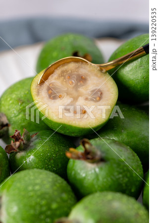 Macro of a half-cut feijoa fruit with a spoon Macro of a half-cut feijoa fruit with a spoon 139220535
