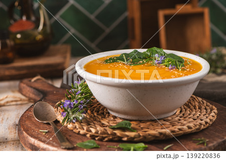 Creamy Pumpkin Soup with Fresh Herbs and Edible Flowers in a Rustic Kitchen Setting Creamy Pumpkin Soup with Fresh Herbs and Edible Flowers in a Rustic Kitchen Setting 139220836