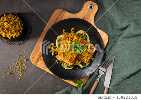 Roasted Tofu with Herb Crust and Sauteed Greens on a Black Plate 139221019