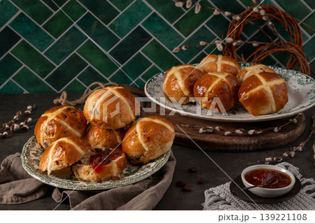 Easter Hot Cross Buns Display with Fruit Jam and Green Herringbone Tile Background 139221108