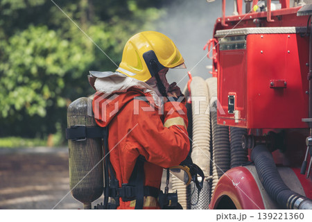 Fireman prepare equipment fighting extinguisher at fire engine truck. Firefighter fighting with smoke flame using fire hose, tube, chemical water foam spray at truck. Fireman wear hard hat protection Fireman prepare equipment fighting extinguisher at fire engine truck. Firefighter fighting with smoke flame using fire hose, tube, chemical water foam spray at truck. Fireman wear hard hat protection 139221360