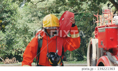 Fireman prepare equipment at fire engine truck. Man hand connect water tube with fire truck fighting extinguisher. Firefighter using fire hose, tube, chemical water foam spray police rescue training 139221363