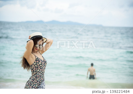 Cheerful asian woman barefoot walking on tropical summer beach. Woman walking along wave of sea water and sand on the beach. Enjoyment barefoot walk outdoor with freedom. Relaxation Travel Concept. Cheerful asian woman barefoot walking on tropical summer beach. Woman walking along wave of sea water and sand on the beach. Enjoyment barefoot walk outdoor with freedom. Relaxation Travel Concept. 139221484