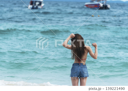 Cheerful asian woman barefoot walking on tropical summer beach. Woman walking along wave of sea water and sand on the beach. Enjoyment barefoot walk outdoor with freedom. Relaxation Travel Concept. Cheerful asian woman barefoot walking on tropical summer beach. Woman walking along wave of sea water and sand on the beach. Enjoyment barefoot walk outdoor with freedom. Relaxation Travel Concept. 139221490