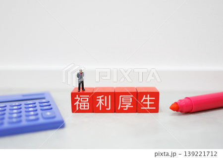 福利厚生。電卓とミニチュアビジネスマン。赤いブロックに文字 139221712