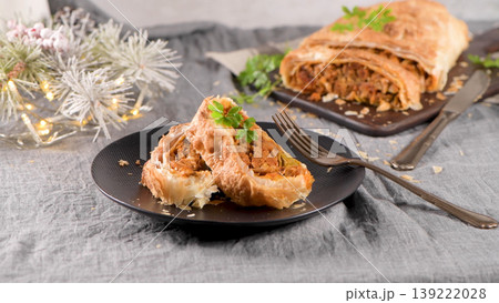 Savory Christmas Meat Strudel Slices Served on a Black Plate with Festive Holiday Decor 139222028