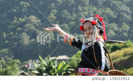 Smiling ethnic woman in traditional tribal dress gesturing with hand in rural village, showing cultural pride, hospitality, and joyful lifestyle in scenic nature Smiling ethnic woman in traditional tribal dress gesturing with hand in rural village, showing cultural pride, hospitality, and joyful lifestyle in scenic nature 139222911