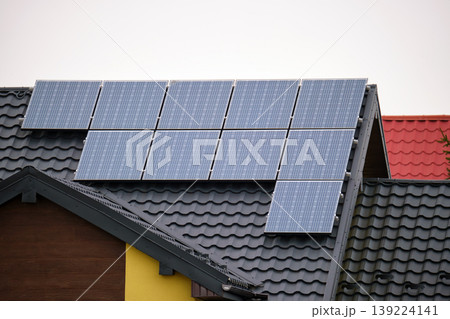 Private home roof covered with solar photovoltaic panels for generating of clean ecological electric energy in suburban rural town area. Concept of autonomous house Private home roof covered with solar photovoltaic panels for generating of clean ecological electric energy in suburban rural town area. Concept of autonomous house 139224141