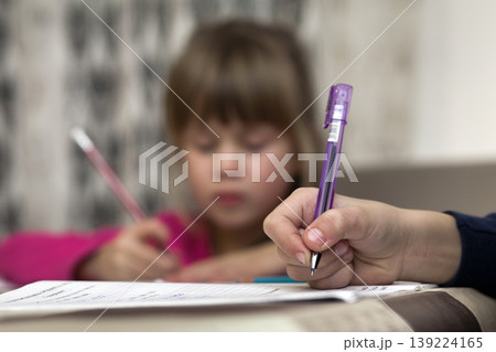 Portrait of cute pretty little serious child girl drawing with pencil on paper on blurred background. Art education, creativity, doing homework and children activities concept. 139224165
