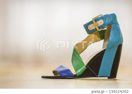 One colorful bright blue, green and yellow leather strap female shoe sandal on high black platform isolated on light copy space background. Style and fashion, modern comfortable footwear for summer. 139224202