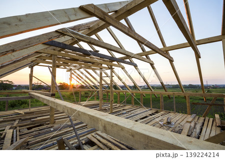 New wooden house under construction. Close-up of attic roof frame against clear sky from inside. Ecological dream home of natural materials. Building, construction and renovation concept. 139224214