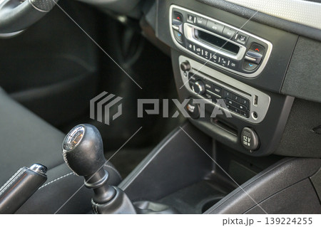 Luxurious car black leather interior. Close-up detail of handbrake manual brake and gearshift stick on blurred dashboard background. Transportation, design, modern technology concept. 139224255