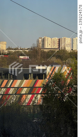Modern building with colorful design against urban skyline. 139224578